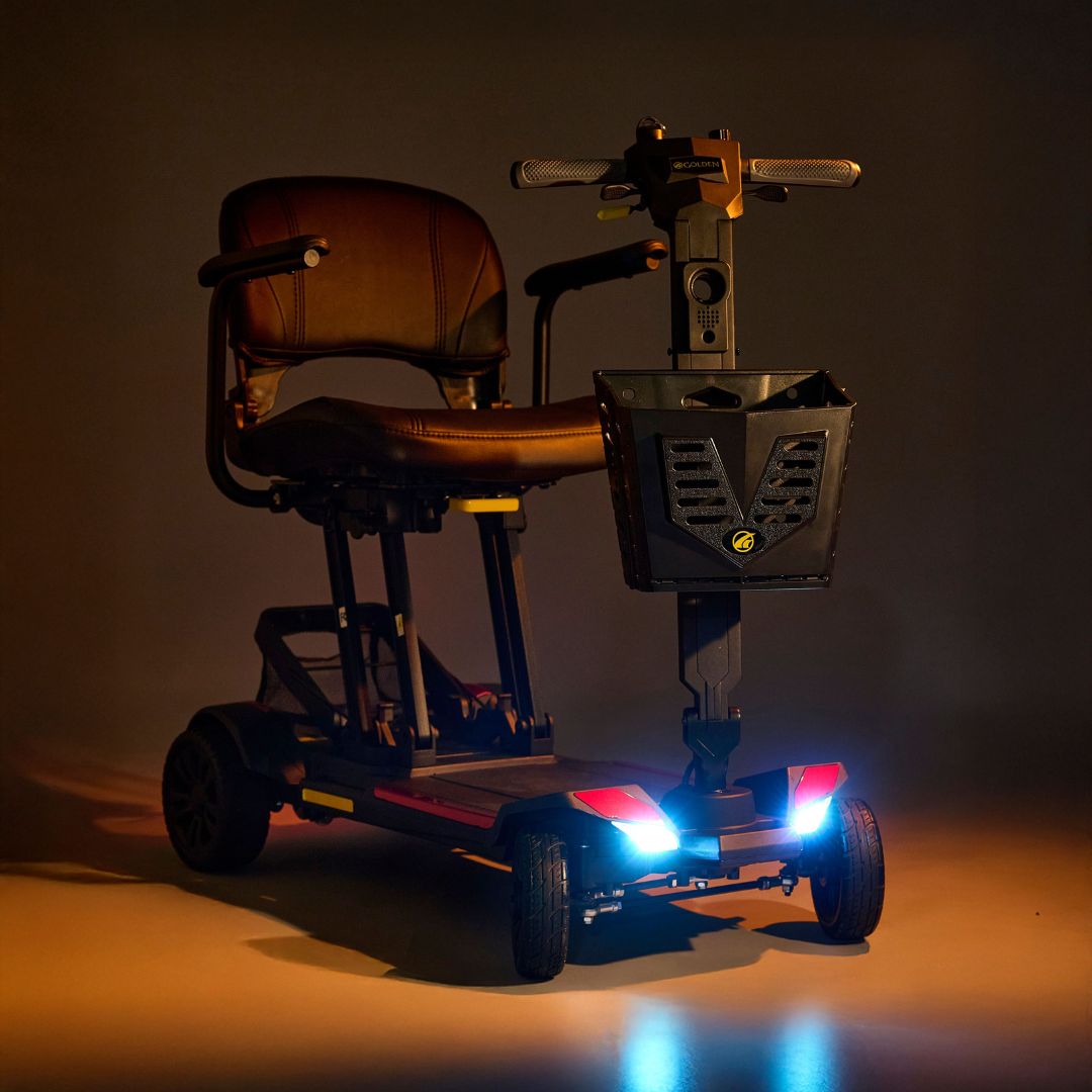Buzzaround CarryOn Scooter by Golden Technologies with visible lights on a dark background