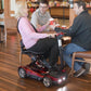 Woman sitting on EV Rider Transport 4AF Automatic Folding Travel Mobility Scooter in Red at lunch with friends.